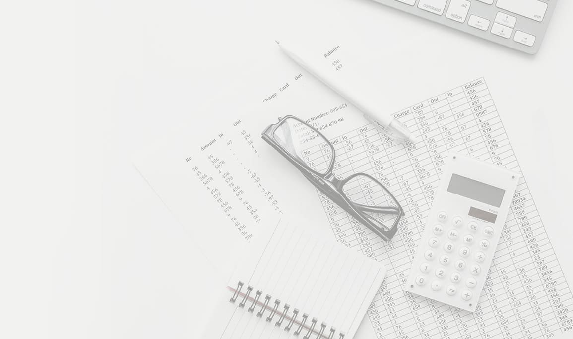 Ein weißer Schreibtisch, auf dessen Oberfläche ein Taschenrechner, eine Brille und ein Stift ordentlich angeordnet sind.