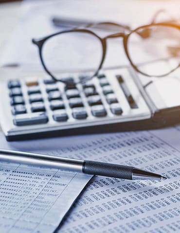 Eine Nahaufnahme eines Stifts und einer Brille auf einem Finanzdokument, die den Schwerpunkt auf die finanzielle Bewertung und Planung legt.